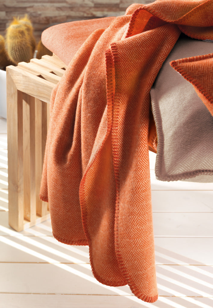 Schurwoll Plaid Aberdeen von Eagle Products aus reiner Merino Schurwolle drapiert auf einer Holzbank mit Kissen