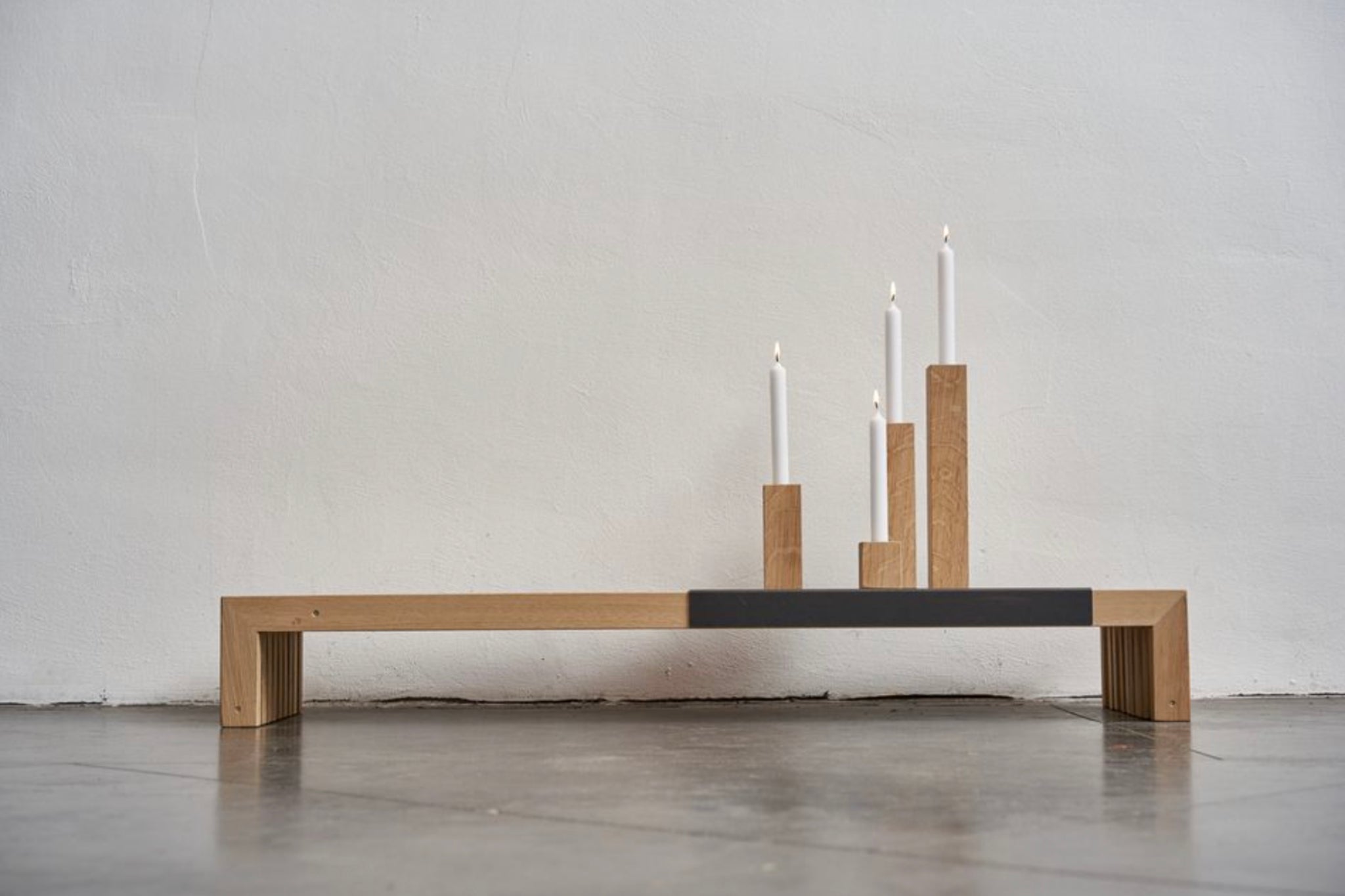 Kerzenquartett von Raumgestalt - vier unterschiedlich hohe Kerzenhalter aus Eiche für Stabkerzen, arrangiert auf einer Holzbank
