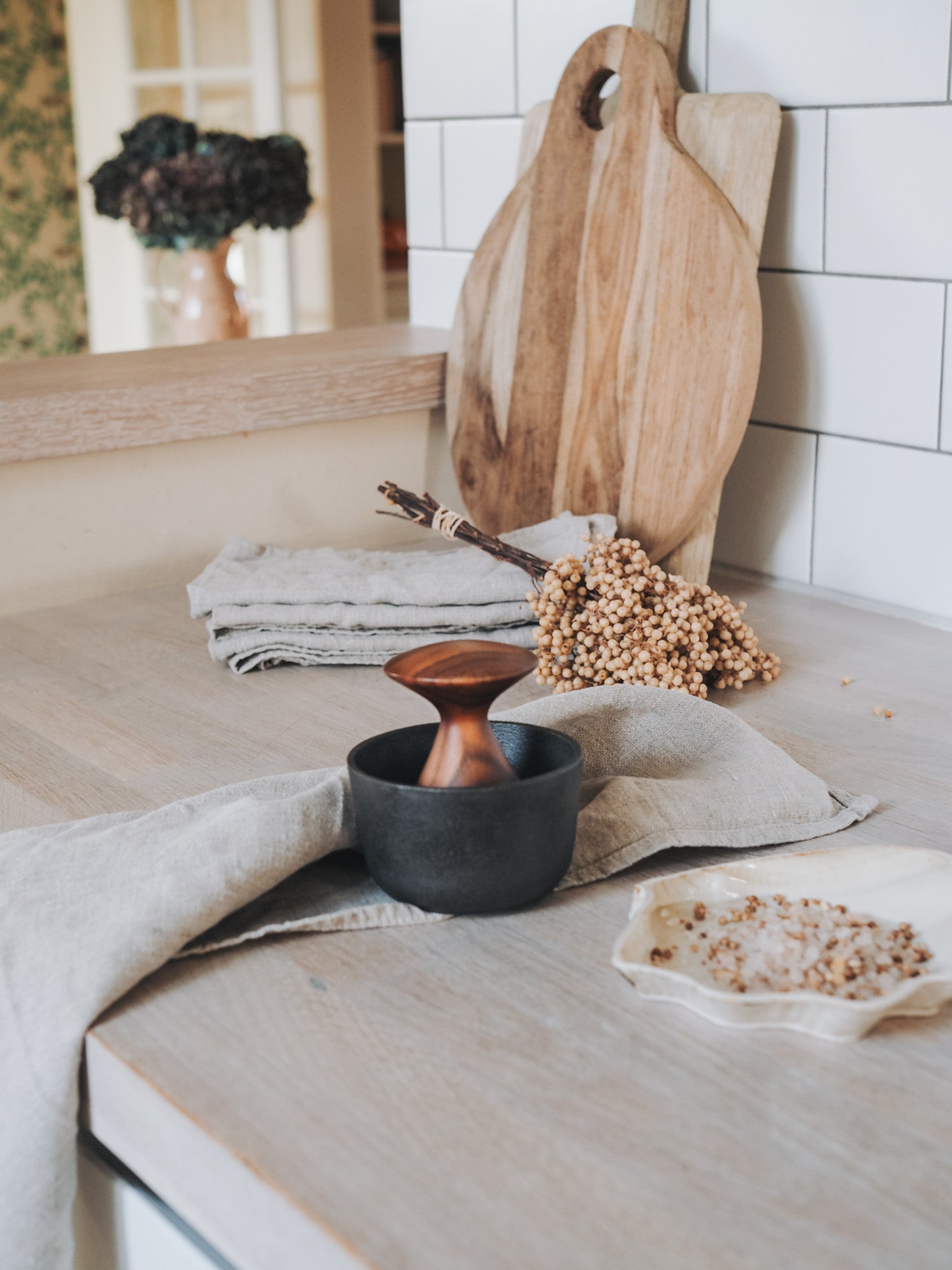 Kiruna Mörser aus Gusseisen mit Akazienholz-Stößel und frisch gemahlenen Gewürzen auf Keramikteller