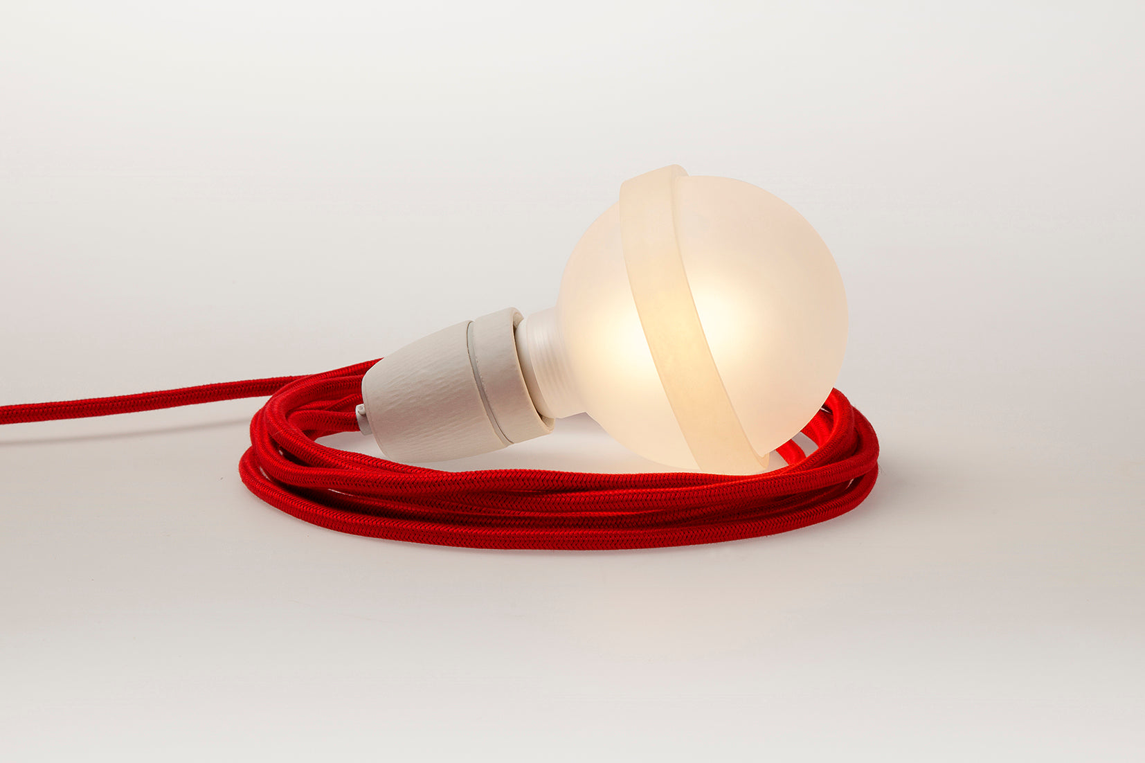 Rote Lampe von Raumgestalt mit rotem Textilkabel